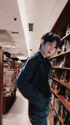 a young man standing in front of a bookshelf with his hands on his hips