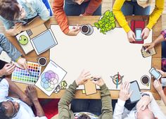 people sitting around a table with their hands on top of each other