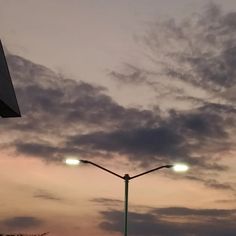 the street lights are lit up in the sky at dusk, as seen from across the street