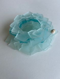 a piece of glass sitting on top of a white table next to a bead