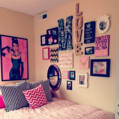 a bedroom with pink and black decor on the wall, pictures above the headboard