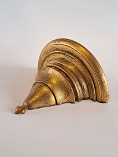 a gold object that is shaped like a snail on a white surface with no one around it