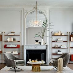 a living room filled with furniture and a fire place in front of a mirror on the wall