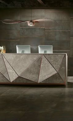 a modern reception table with two chairs and a laptop on it in front of a wall