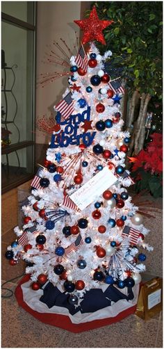 a white christmas tree with red, white and blue decorations on it's base