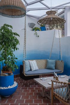 a living room with blue and white walls, two hanging chairs and a couch in front of a potted plant