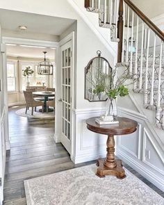 an entry way with a table, mirror and stairs