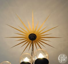 a chandelier hanging from the ceiling with three light bulbs on each side and one bulb turned upside down