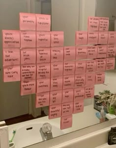 pink sticky notes are hanging on the wall in front of a bathroom mirror that is covered with writing