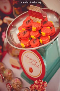 a bowl filled with red and yellow cookies on top of a table next to cupcakes