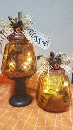 two glass jars with lights in them sitting on a checkered tablecloth covered table