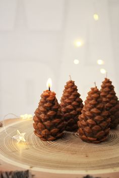 three pine cone candles sitting on top of a wooden table