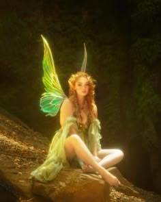 a woman dressed as a fairy sitting on a rock