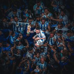 a soccer player is holding his trophy in the middle of a group of people who are all wearing blue and white striped shirts