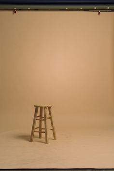 an empty photo studio with a stool in the foreground and a light on the wall behind it