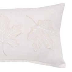 a white pillow with embroidered leaves on it