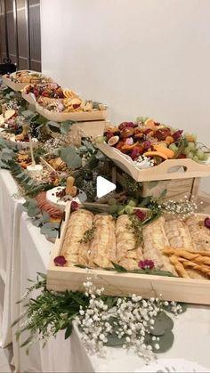 a long table with many trays of food sitting on it's sides, along with flowers and greenery