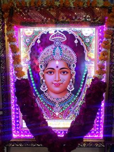 an idol is displayed in the middle of a room with purple flowers and garlands around it