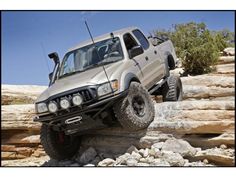 a silver truck is jumping over rocks in the air