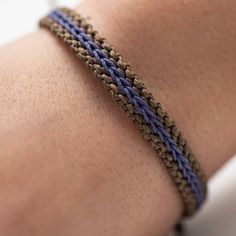 a close up of a person's arm wearing a blue and brown braided bracelet