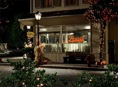 an outside view of a restaurant at night with lights on the windows and pumpkins all around