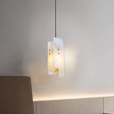 a modern light fixture hanging from the ceiling in a room with white walls and furniture