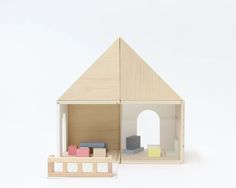 a wooden doll house with furniture in front of it on a white background and an open door