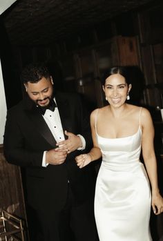 a man in a tuxedo standing next to a woman in a white dress