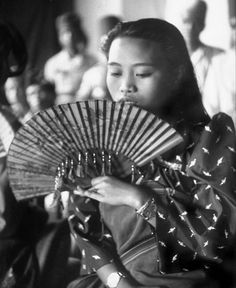 an old photo of a woman holding a fan