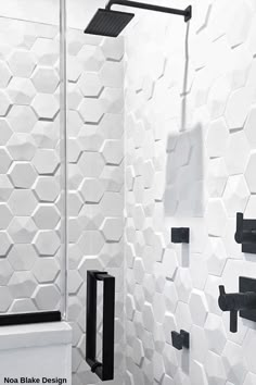 a white bathroom with black fixtures and hexagonal tiles on the wall behind it