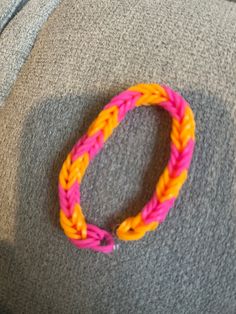 an orange and pink bracelet sitting on top of a gray chair