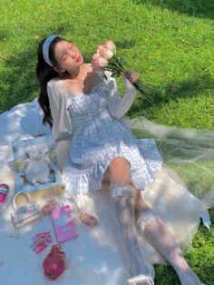 a woman laying on the ground with flowers in her hand and other items around her