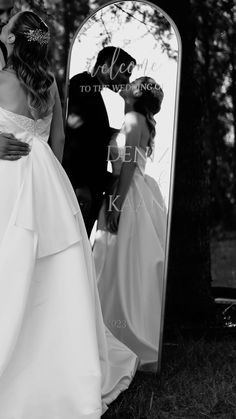 a bride and groom standing in front of a mirror with the reflection of their wedding day