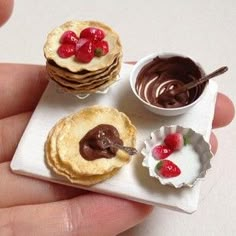 miniature desserts are being held in the palm of someone's hand, with chocolate and cherries on top