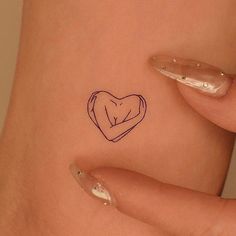 a woman's stomach with a small heart tattoo on her left side ribcage