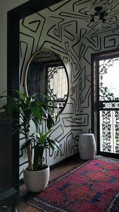 a room with a rug, mirror and potted plant