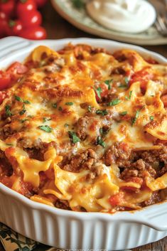 a casserole dish with meat, cheese and tomatoes on the side is ready to be eaten