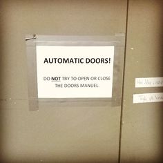 an automatic door sign is posted on the side of a metal door that says automatic doors do not try to open or close the doors manual