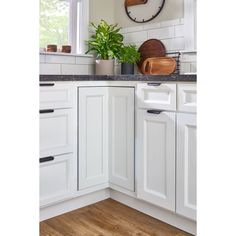 a kitchen with white cabinets and a clock on the wall