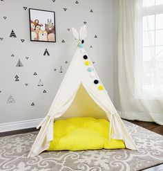 a teepee tent bed in a child's room with white walls and yellow pillows