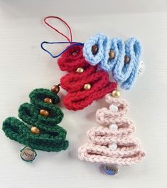 three crocheted christmas tree ornaments on a white surface