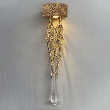 a wall light that is made out of glass and gold leafy branches, hanging on a gray wall