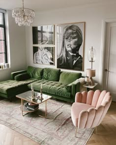 a living room with green couches and pictures on the wall above them, as well as a chandelier