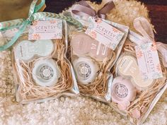 three packaged soaps sitting on top of a white carpet next to a ribbon and tag