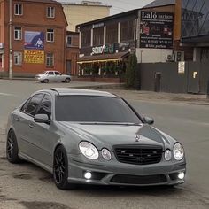 a mercedes benz is parked on the side of the road in front of some buildings