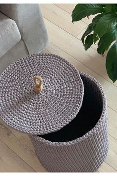 two round baskets sitting on top of a wooden floor next to a couch and potted plant