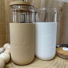 two mason jars sitting next to each other on top of a wooden table with eggs around them