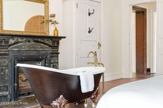 a bath tub sitting next to a fireplace in a bedroom