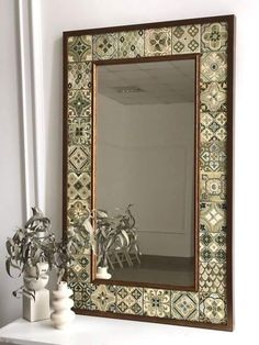 a mirror sitting on top of a white shelf next to a vase and potted plant