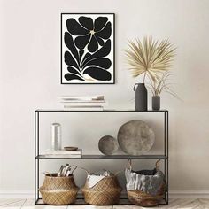 a black and white flower is hanging on the wall above a shelf with some baskets